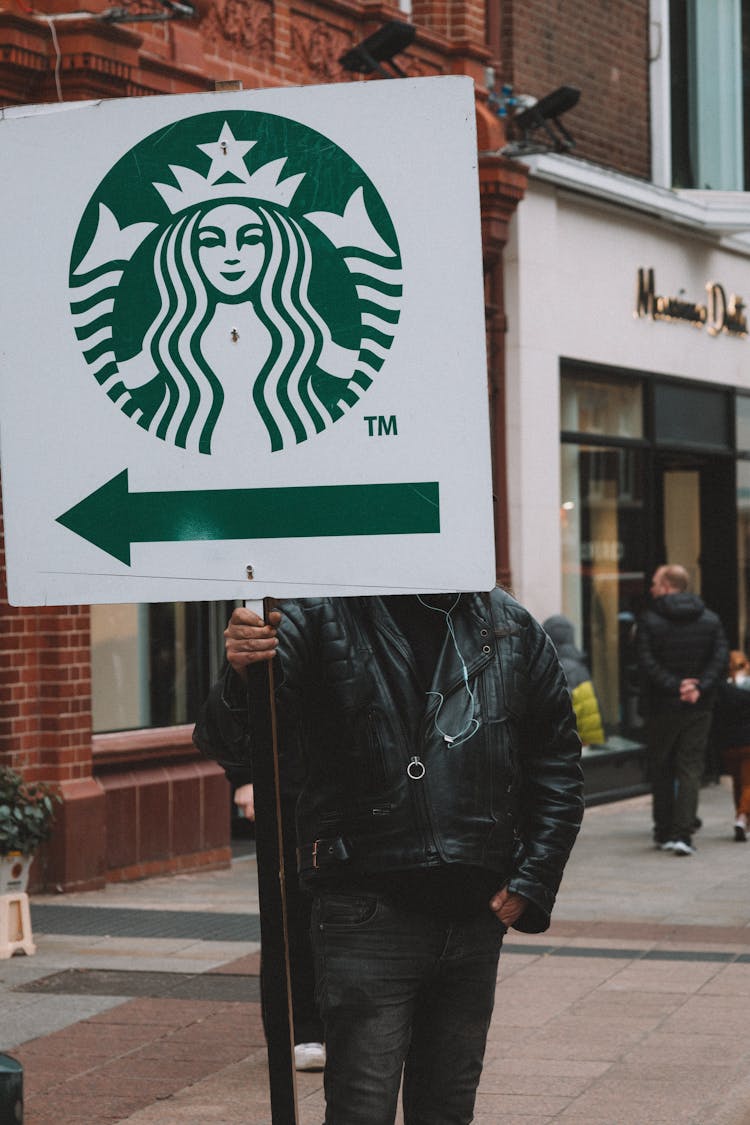 Person Standing With Banner With Direction To Starbucks