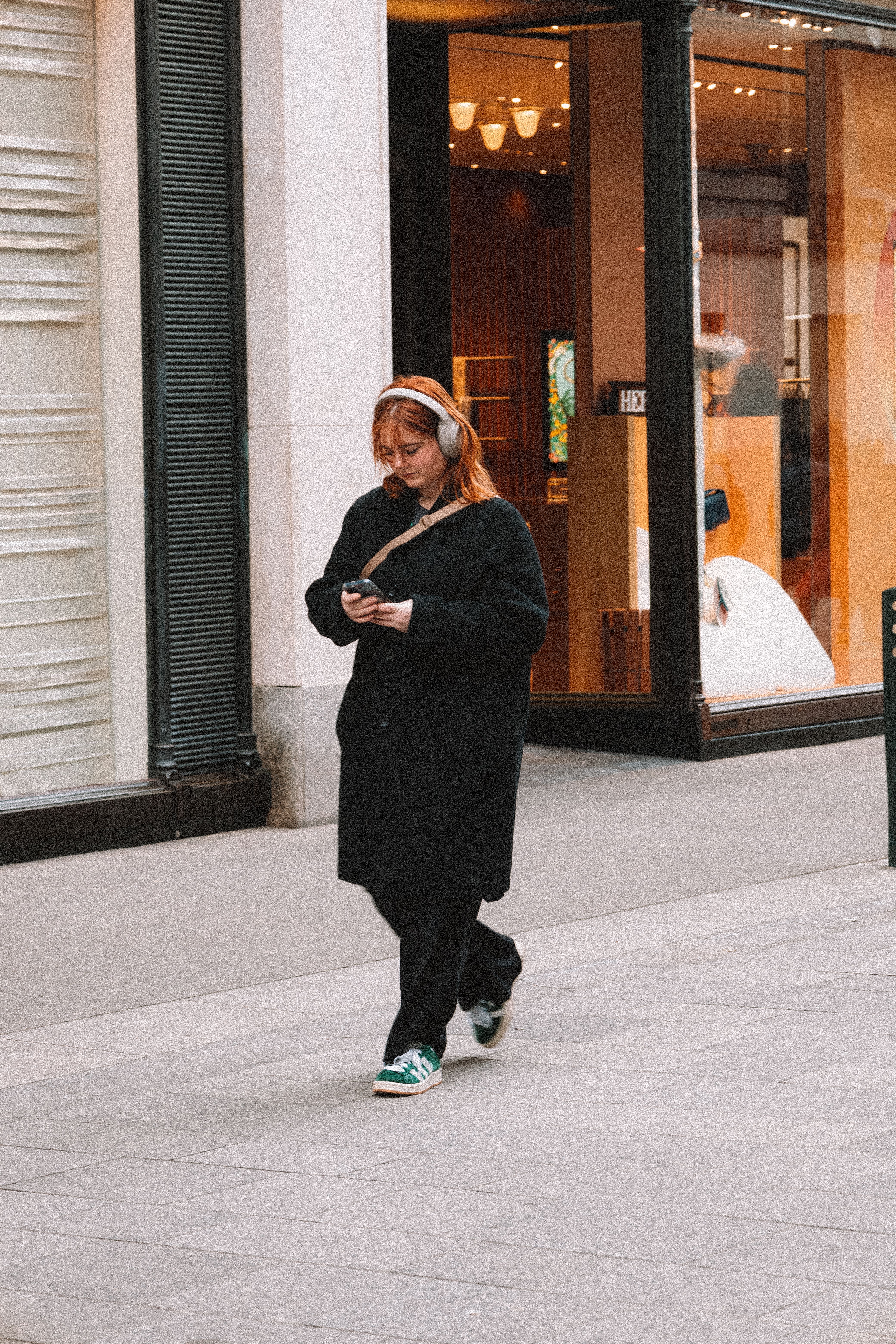 Woman in Black Coat Walking with Smartphone on Sidewalk · Free Stock Photo