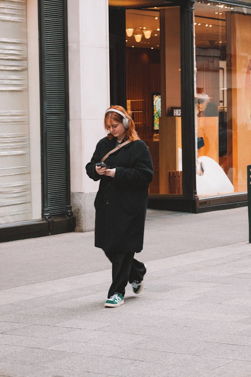 A woman walking down the street with her phone