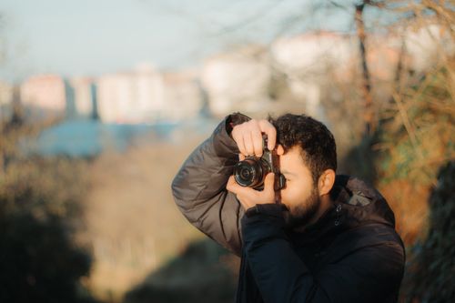 Free Male photographer taking a photo outdoors in fall with blurred background. Stock Photo