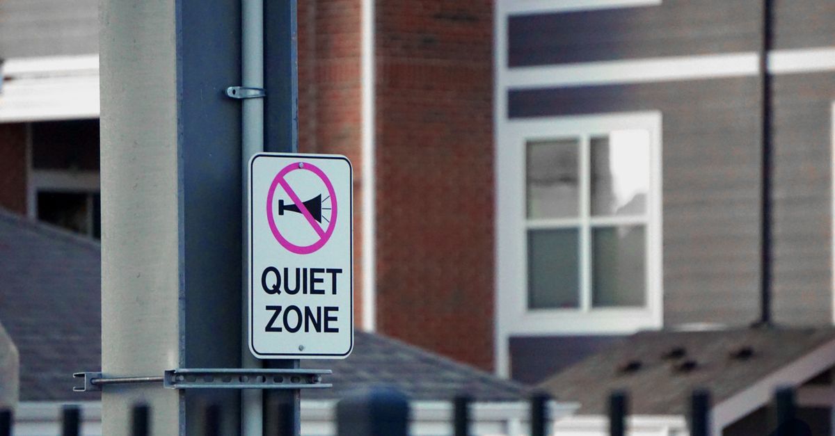 Quiet zone sign on pole in front of urban residential buildings, conveying silence and peace.
