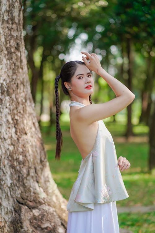 A woman in a white dress is posing in the park