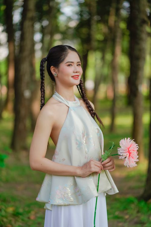 A woman in a white top and skirt holding a flower