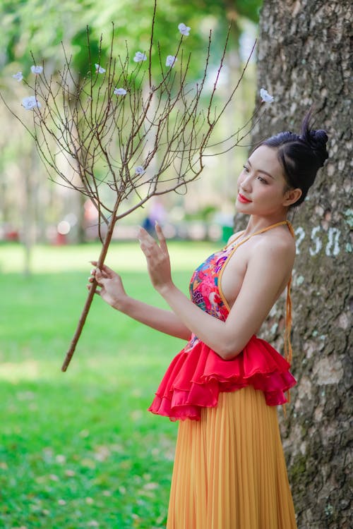 A woman in a colorful dress holding a branch