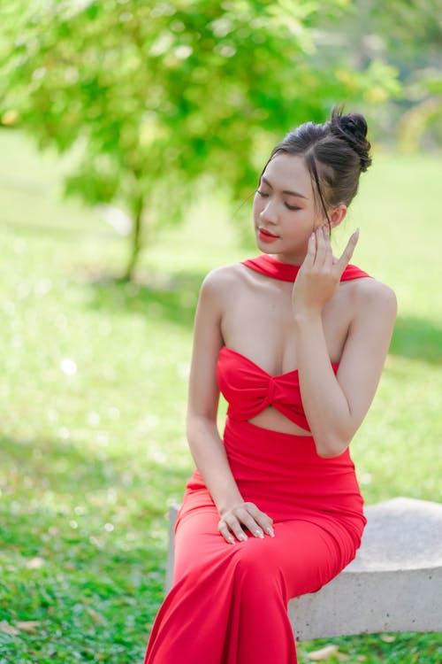 A woman in a red dress sitting on a bench
