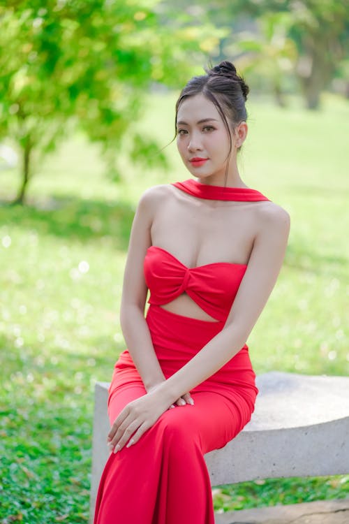 A woman in a red dress sitting on a bench