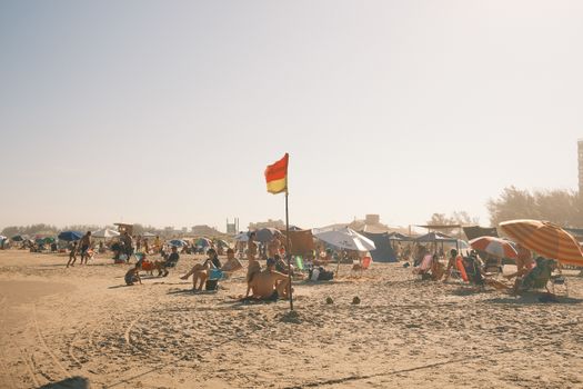 A lively beach scene featuring vacationers enjoying a sunny day under colorful umbrellas, capturing summer vibes.