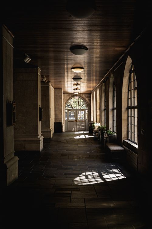 Free A sunlit corridor with arched windows and shadows creating a serene atmosphere. Stock Photo