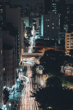 Aerial view of São Paulo city streets at night with vibrant light trails and illuminated urban landscape.