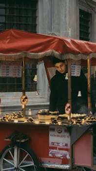 Teenage vendor selling roasted chestnuts at an outdoor food stand in Istanbul.