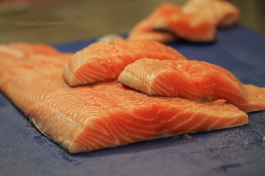 Close-up of fresh salmon fillets on a blue cutting board, ready for cooking.