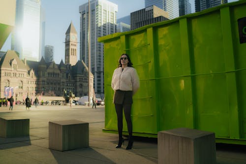 A woman standing in front of a green container