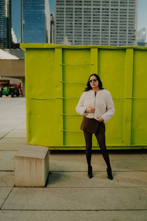 A woman standing in front of a green container
