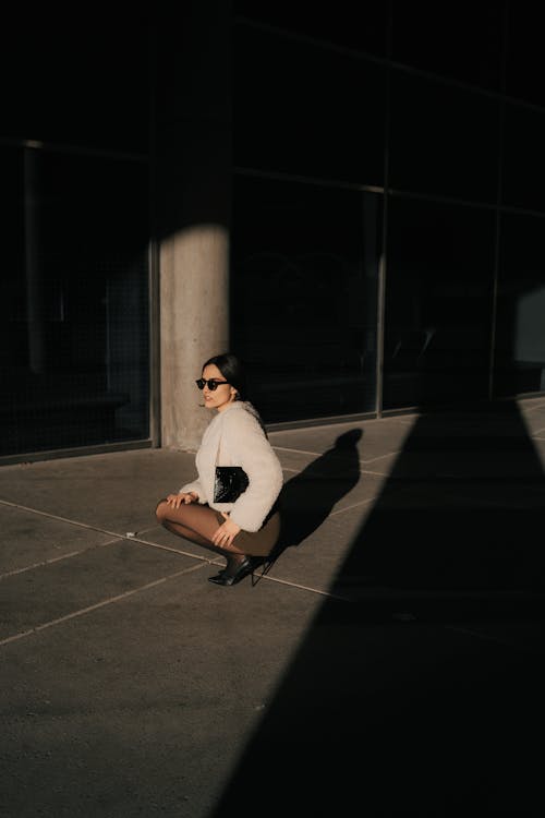 A woman sitting on the ground in front of a building