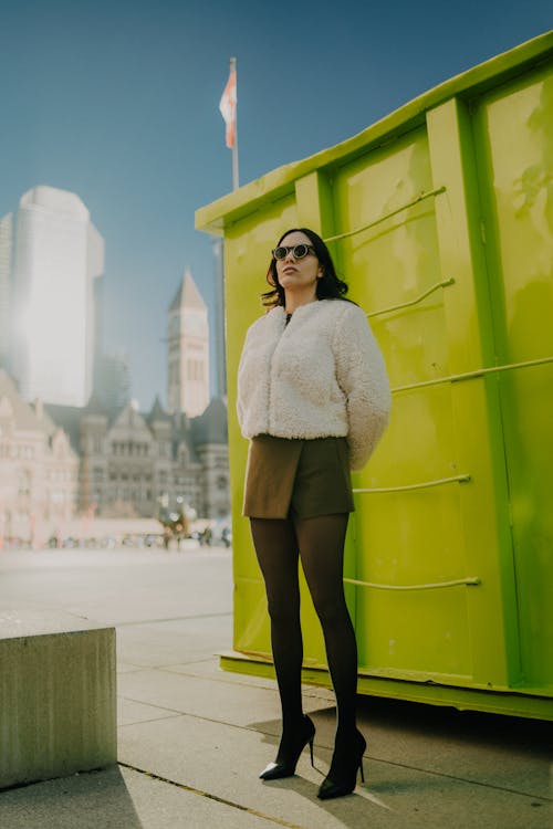 A woman in a fur coat standing in front of a green container
