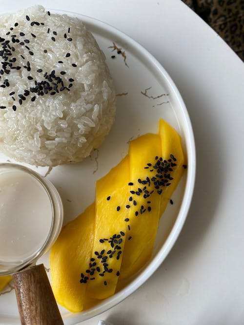 A plate with rice, mango and sesame seeds
