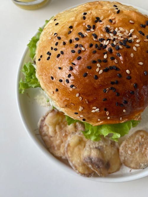 A burger with sesame seeds and onions on a plate