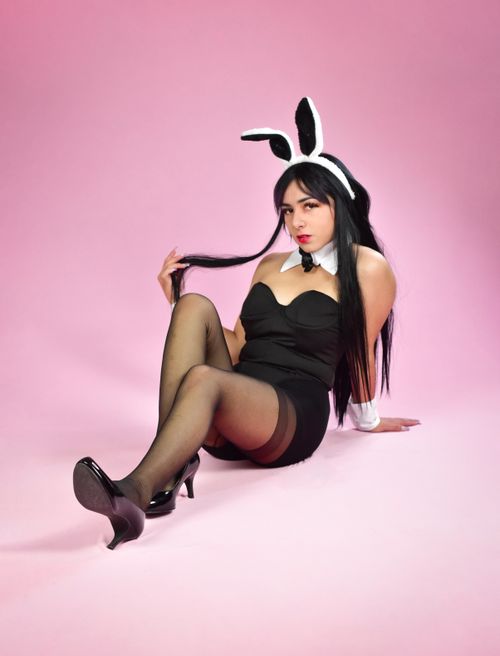 Free A woman in a playful bunny costume poses elegantly on a pink background. Stock Photo