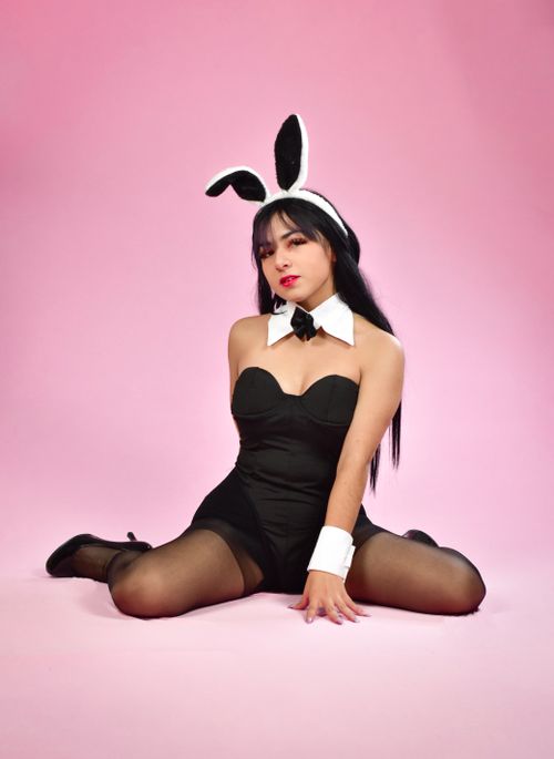Free Young woman posing in a bunny costume against a pink backdrop. Stock Photo