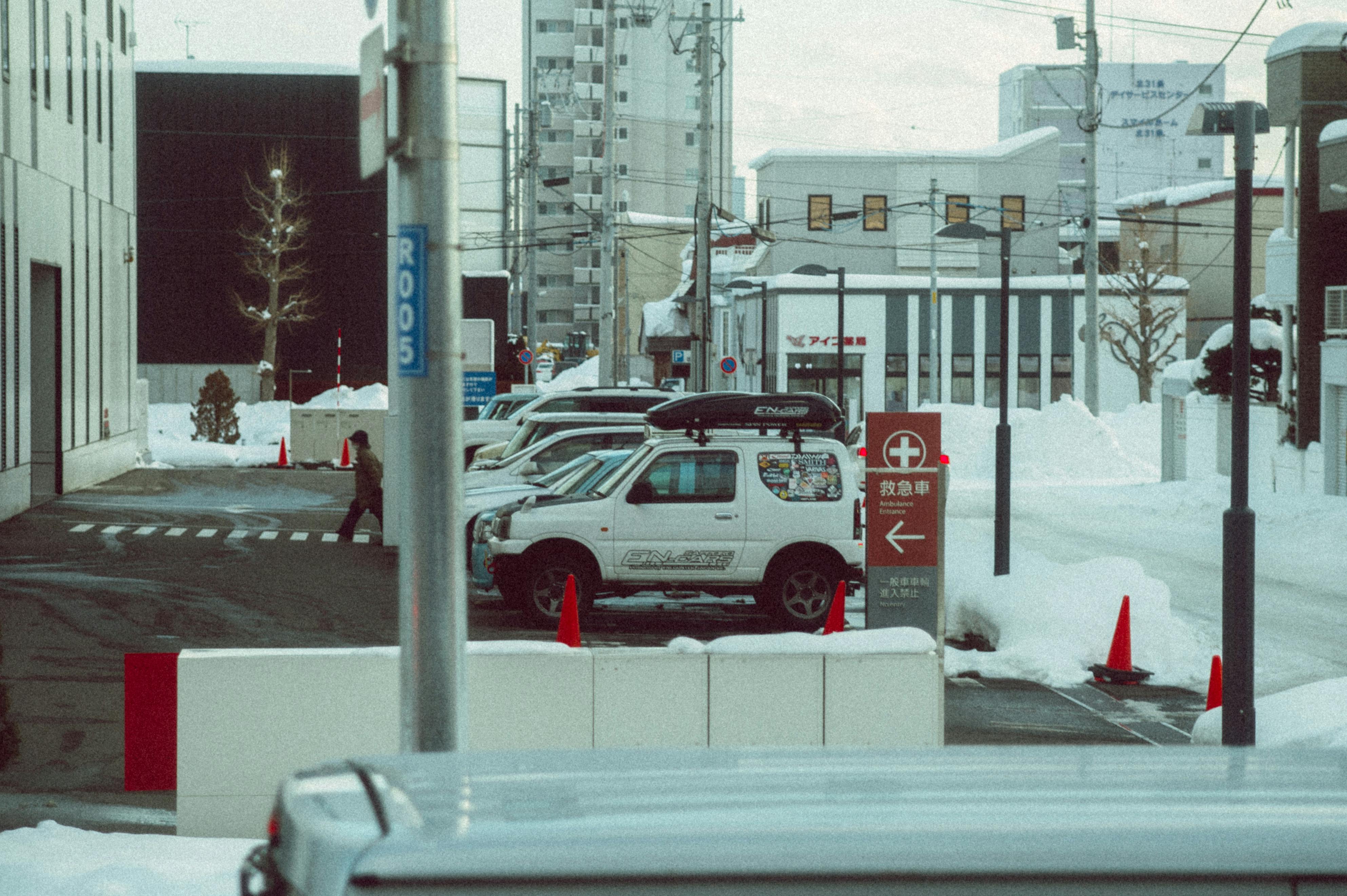 Snow-covered urban street in Hokkaido, Japan with cars and buildings, showcasing a serene winter morning.