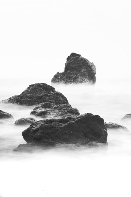 Eerie black and white photo of mist-covered rocks in the San Francisco Bay.