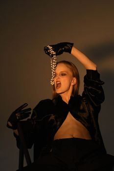Stylish portrait featuring a woman in black attire holding pearls, showcasing elegance and luxury.