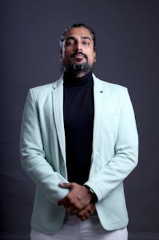 Elegant portrait of a bearded man in a mint blazer posing confidently in a studio setting.