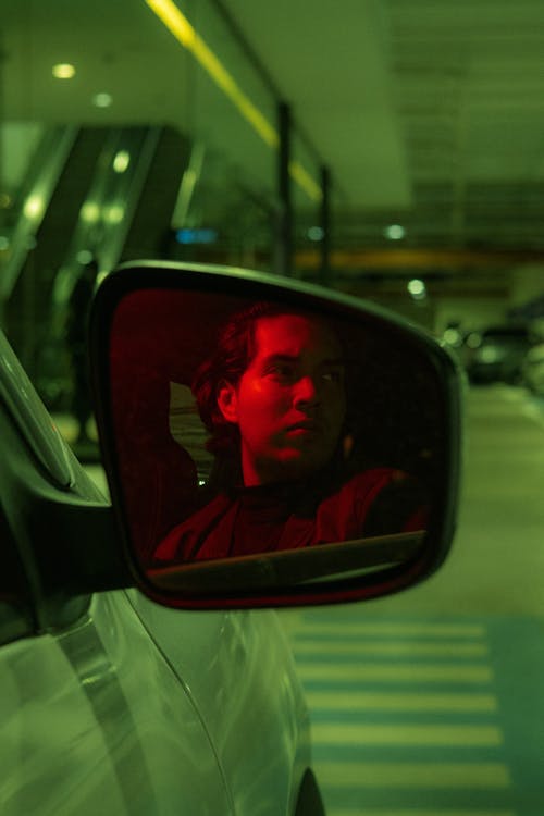 A man in a car looking in the rearview mirror
