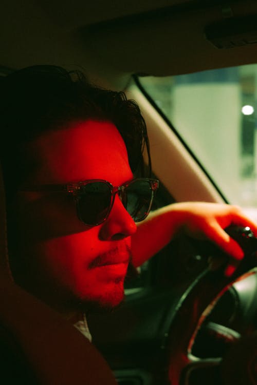 A man in sunglasses driving a car at night