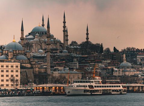 Magnificent view of the Suleymaniye Mosque with a ferry on the Bosphorus in Istanbul at sunset.