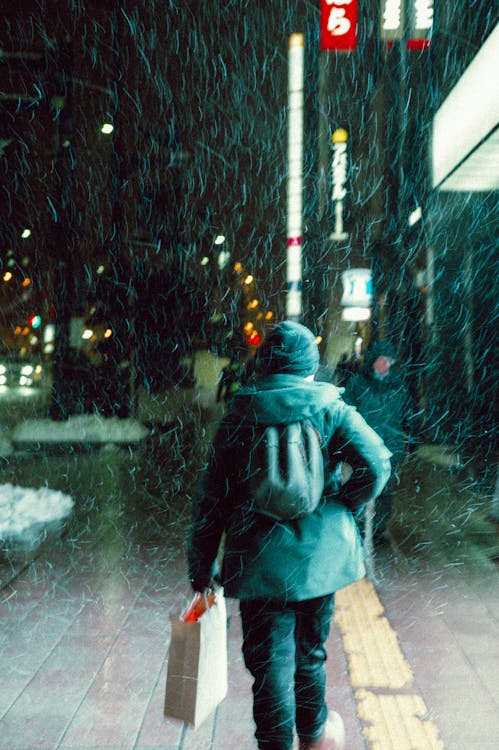 Person Walking Through Rain in a City