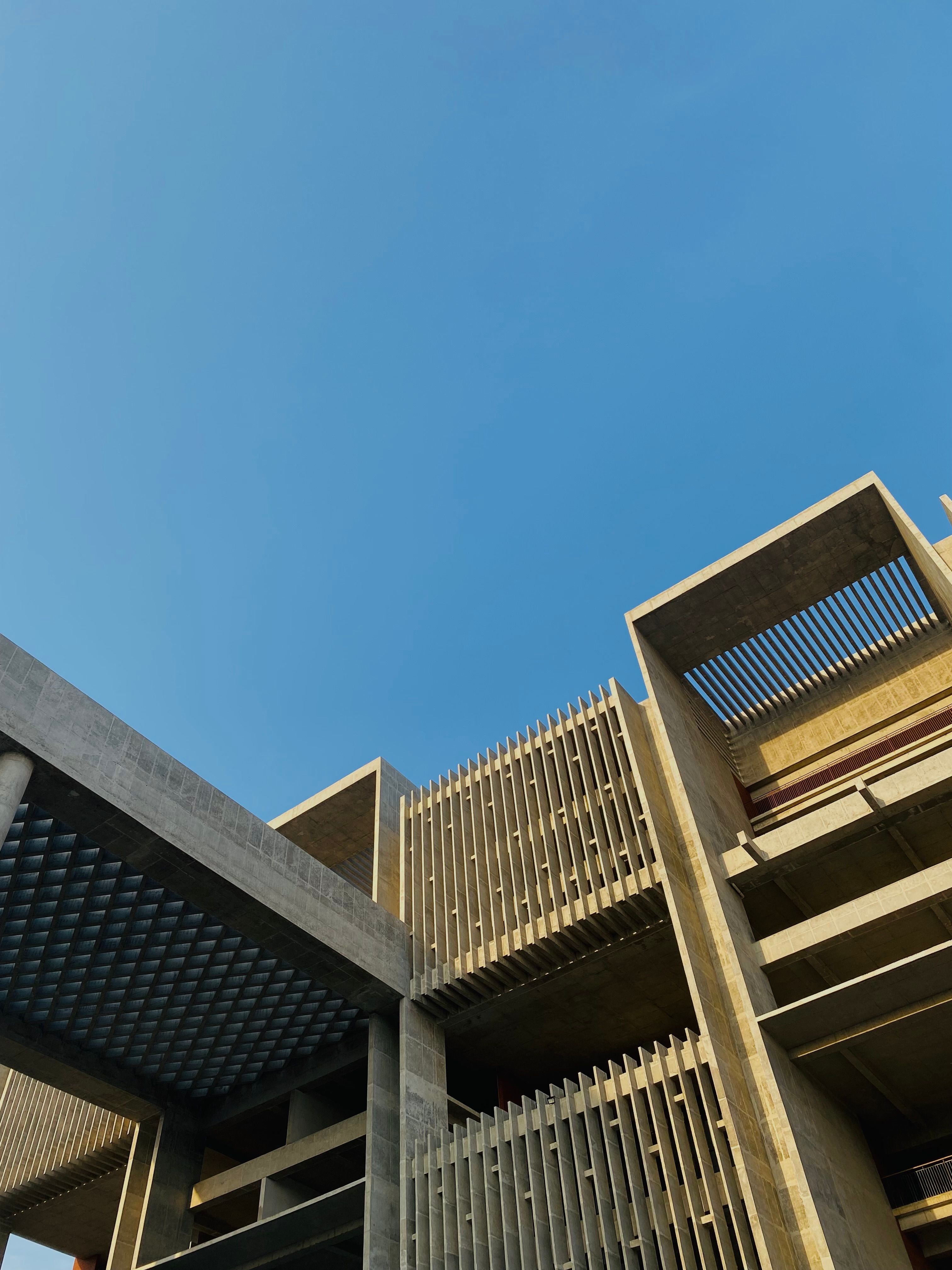 Striking brutalist architecture with a clear blue sky backdrop, showcasing modern design through vertical and angular forms..