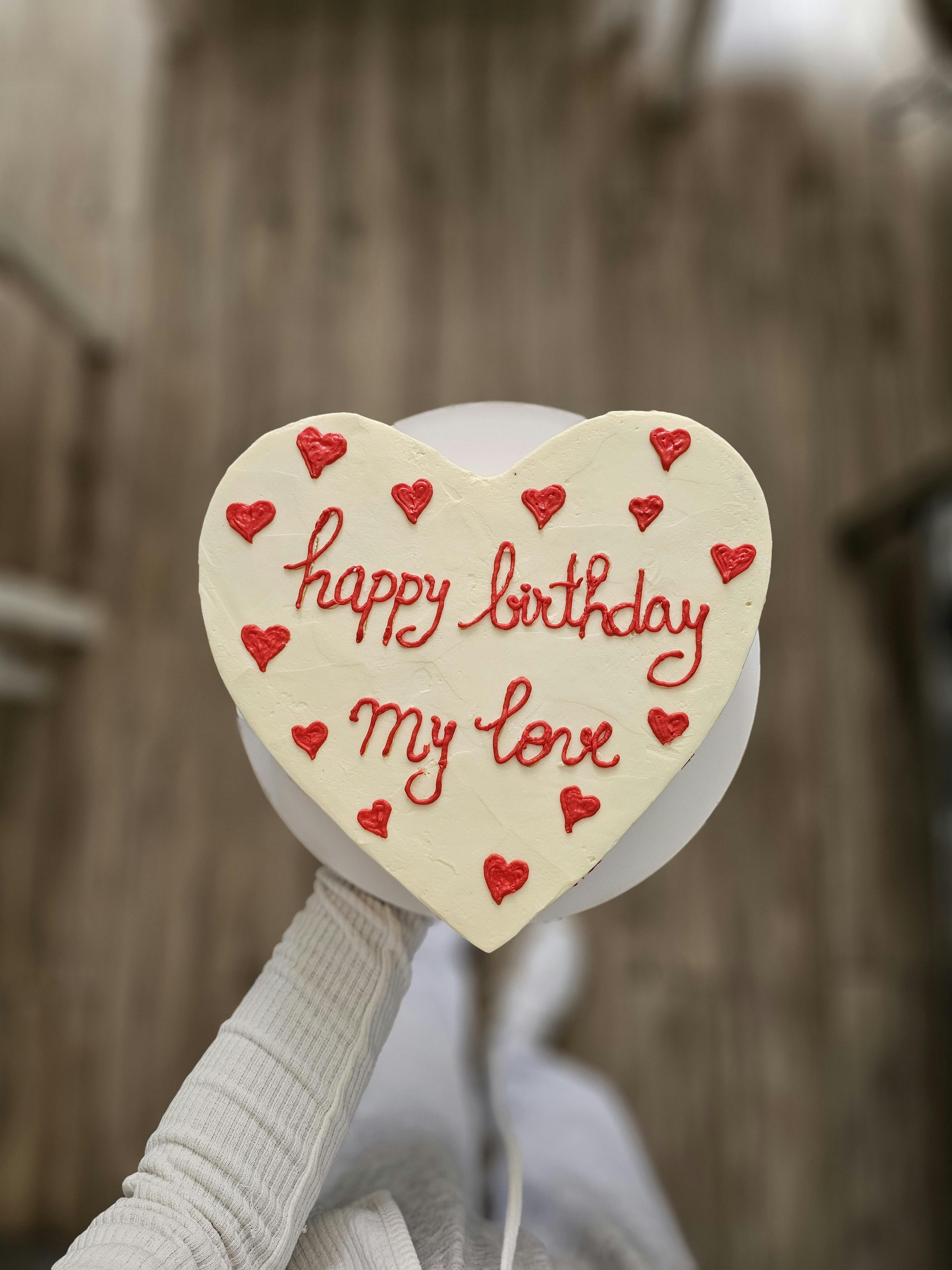 Delightful heart-shaped cake with 'Happy Birthday My Love' message and red heart decorations.