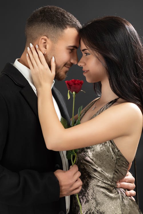 A man and woman are kissing each other with a red rose