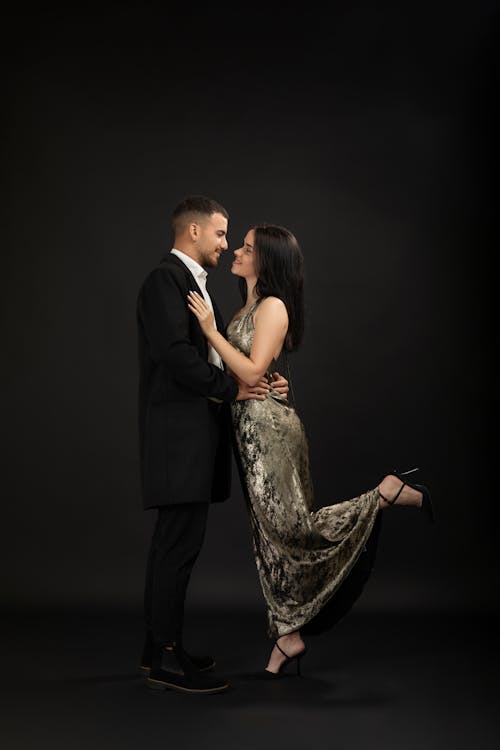 A man and woman in formal attire pose for a photo