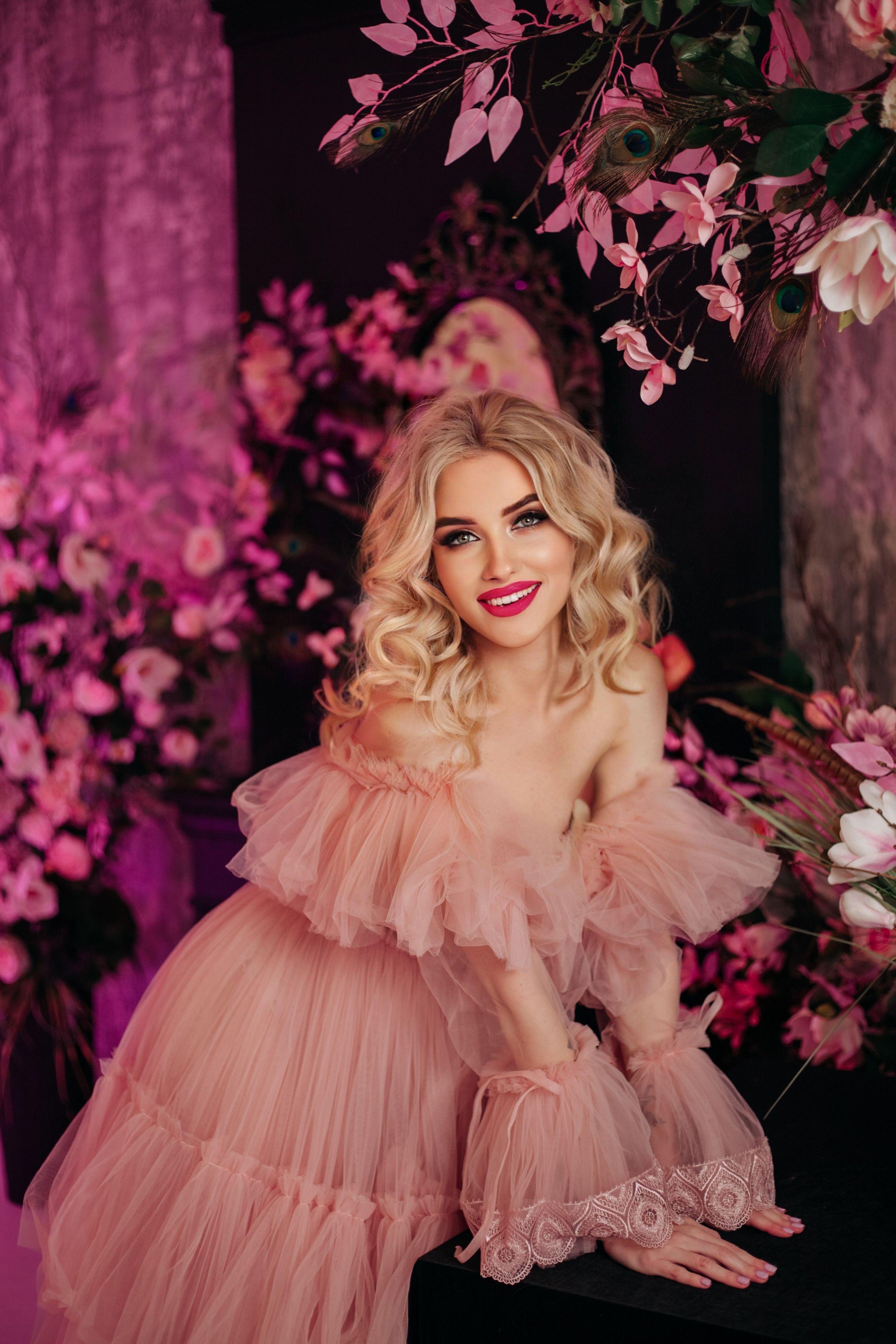 Young Woman Posing in a Pink Tulle Dress among Flower Arrangements