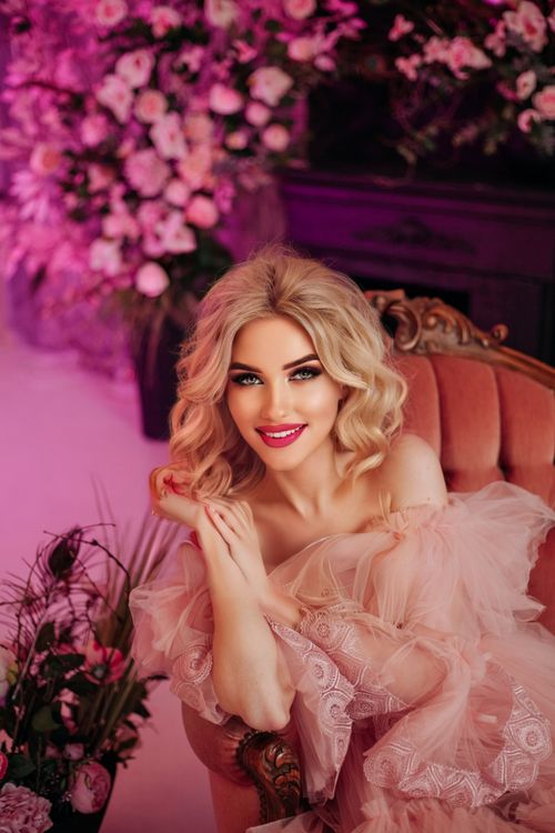 Free Elegant woman in pink dress posing in a studio with a floral background. Glamour and sophistication in fashion photography. Stock Photo
