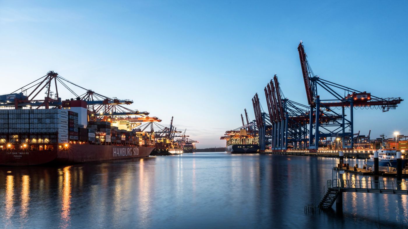 Container ships and illuminated cranes reflected in the water at Hamburg port at dusk
