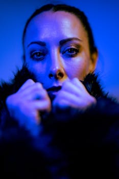 Dramatic close-up portrait of a woman in blue lighting wearing a fur coat, exuding a cinematic fashion feel.
