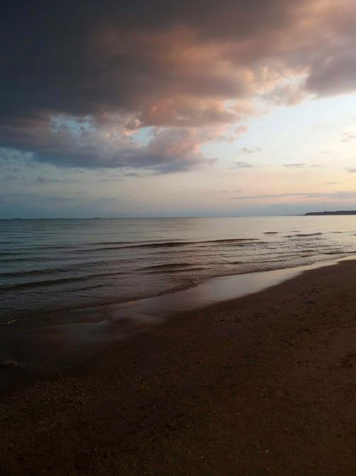 Free A serene beach scene featuring calm waves and a stunning sunset sky, perfect for a tranquil escape. Stock Photo