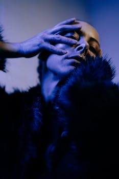 Moody portrait of a woman in a fur coat under blue lighting, showcasing winter fashion.