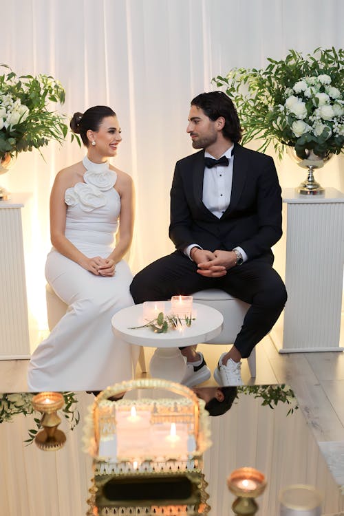 A man and woman sitting on a couch in front of a white backdrop