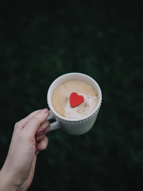 Woman Hand Holding Coffee Cup with Heart Cookie