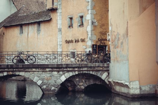 Charming historic bridge over a canal in old town Annecy, France, featuring rustic architecture.