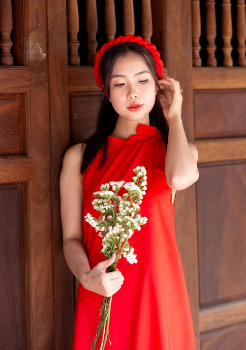 Young Woman Wearing a Red Dress and Holding Flowers 