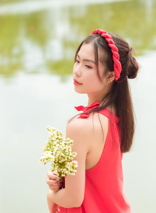 A woman in a red dress holding a bouquet of flowers