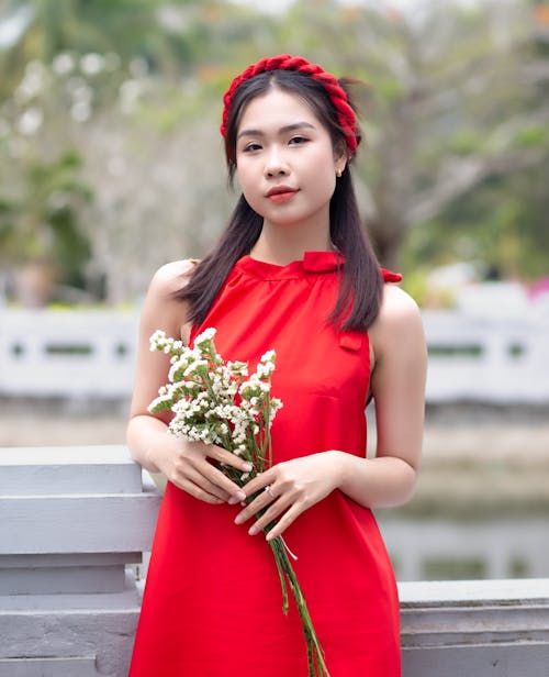A woman in a red dress holding flowers