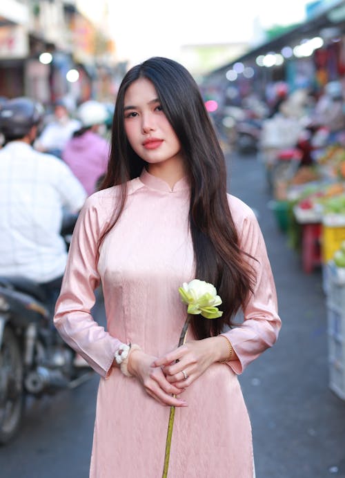 Young Brunette in a Pink Dress Standing on a Street in City 