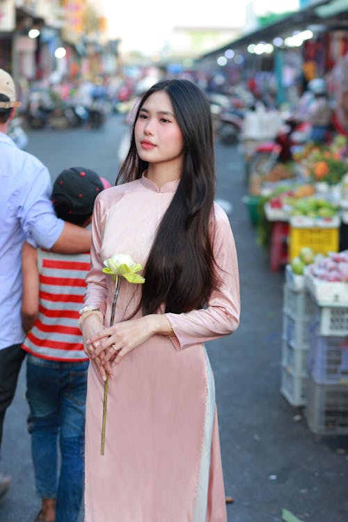 A woman in a pink dress is standing in a market