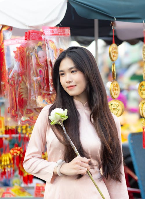 A woman in a pink dress holding a flower